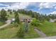 Aerial view showing a home on a verdant lot with mature trees, a deck, and a long driveway at 24030 San Isabel Rd, Indian Hills, CO 80454