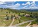 An aerial view features the home in a scenic, wooded area with rolling hills and mountain views at 24030 San Isabel Rd, Indian Hills, CO 80454