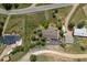 Aerial view captures the property layout with multiple buildings, a winding driveway, and mature landscaping at 24030 San Isabel Rd, Indian Hills, CO 80454