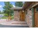 Close-up of the front entrance with stone veneer, wooden door and hanging flower baskets at 24030 San Isabel Rd, Indian Hills, CO 80454