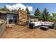 Spacious outdoor deck with a stone fireplace, ample seating, and a serene setting at 24030 San Isabel Rd, Indian Hills, CO 80454