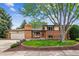 Charming brick home featuring a lush lawn, mature tree, and a cozy front porch seating area at 2990 S Jay St, Denver, CO 80227