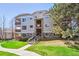 Multi-story building with stone accents, multiple balconies, manicured lawn, and mature trees at 7680 Depew St # 1404, Arvada, CO 80003