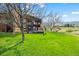 Two-story home with a stone chimney, back deck, lush lawn, and mature trees at 10895 Pheasant Run, Littleton, CO 80125