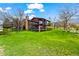 Two-story home with a back deck, lush lawn, mature trees, and a stone chimney at 10895 Pheasant Run, Littleton, CO 80125