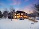 Beautiful back of home with a stone chimney, large windows, and a deck surrounded by snow covered yard at 10895 Pheasant Run, Littleton, CO 80125