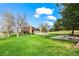 Spacious backyard with lush green grass, patio seating area, mature trees, and two-story home with attached garage at 10895 Pheasant Run, Littleton, CO 80125