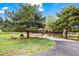 Exterior front view of a home with a stone and wood facade, surrounded by mature trees and lush lawn at 10895 Pheasant Run, Littleton, CO 80125