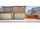 Townhome exterior features a two-car garage, a small patch of rocks, and a wooden fence at 1557 S Dallas Cir, Denver, CO 80247