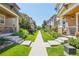 Well-manicured lawns line a sidewalk between townhomes, creating a tranquil neighborhood atmosphere at 1557 S Dallas Cir, Denver, CO 80247