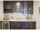 This wet bar features dark cabinetry, a wine rack, marble countertops and a beverage fridge at 1557 S Dallas Cir, Denver, CO 80247