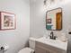 Powder room with modern fixtures, a gray vanity, a decorative mirror, and vintage-inspired artwork at 11418 W Roxbury Ave, Littleton, CO 80127
