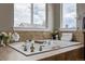 Elegant bathroom featuring a soaking tub with tile surround, decorative accents, and a window view at 11801 E 118Th Ave, Commerce City, CO 80640