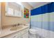 Charming bathroom featuring a vanity, toilet, shower with colorful curtain, and vanity mirror at 2645 Osceola St, Denver, CO 80212