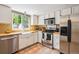 Bright kitchen featuring stainless steel appliances, white cabinets, tile floor, and a large window over the farmhouse sink at 2645 Osceola St, Denver, CO 80212
