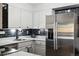 A closer view of the modern kitchen with stainless steel refrigerator and white cabinets with dark hardware at 420 Zang St # 3-208, Lakewood, CO 80228