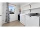 Well-lit laundry room featuring modern appliances and built-in shelving at 6005 E Iowa Ave, Denver, CO 80224