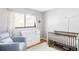 Cozy Bedroom with white changing table, wooden crib, plush rug and window with floral curtains at 1634 S King St, Denver, CO 80219