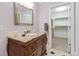 Bathroom featuring a vanity with granite countertop, decorative pulls, and view into a walk-in closet at 2627 E Willamette Ln, Greenwood Village, CO 80121