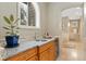Wet bar with wood cabinets, granite countertop, a plant, and an arched window with backyard views at 2627 E Willamette Ln, Greenwood Village, CO 80121
