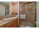 Well-maintained bathroom featuring a walk-in shower, wooden cabinets, tile countertops, and modern fixtures at 34 Normandy Rd, Evergreen, CO 80439