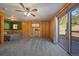 Spacious bedroom with wood paneling, carpeted floors, a ceiling fan, access to the deck, and large windows at 34 Normandy Rd, Evergreen, CO 80439