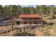 Charming home with red roof and stone accents surrounded by lush trees and a spacious deck at 34 Normandy Rd, Evergreen, CO 80439