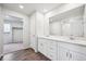 Bathroom featuring a double vanity with quartz countertops, white cabinets, and wood look floors at 1415 Orchard St, Brighton, CO 80601