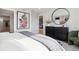 Bright primary bedroom features a large dresser, decorative mirror, and artwork; access to ensuite bathroom at 1415 Orchard St, Brighton, CO 80601
