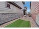 Side yard featuring gravel landscaping, artificial turf, and modern exterior of the home at 6052 N Malta St, Aurora, CO 80019