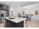 Features an island with a sink, stainless steel appliances, dark cabinets, and an open view of the dining room at 6052 N Malta St, Aurora, CO 80019
