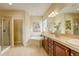 Bright bathroom featuring dual sinks, a soaking tub, a separate shower, and tile flooring at 15004 Verbena St, Thornton, CO 80602