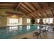 Bright indoor pool area with a vaulted wood beam ceiling, large windows, and comfortable lounge chairs at 15004 Verbena St, Thornton, CO 80602