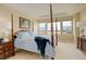 Primary bedroom with tray ceiling, four-poster bed, and a view of the neighborhood at 15004 Verbena St, Thornton, CO 80602