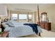 Spacious main bedroom with four-poster bed, tray ceiling, and large windows offering beautiful neighborhood views at 15004 Verbena St, Thornton, CO 80602