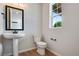 Elegant powder room featuring a pedestal sink, toilet, and window for natural light at 17831 Parkside N Dr, Commerce City, CO 80022