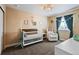 Bedroom featuring a white crib with wood trim, a comfy chair with ottoman, and soft neutral walls at 21088 Randolph Pl, Denver, CO 80249