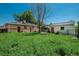 View of the overgrown backyard with a brick house and a detached garage at 10839 Carrol Ln, Northglenn, CO 80233