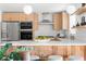 Modern kitchen with stainless steel appliances, light wood cabinets, floating shelves, and eat-in counter at 417 S Pontiac Way, Denver, CO 80210