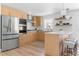 Well-lit kitchen with light wood cabinets, stainless steel appliances, and an island with barstool seating at 417 S Pontiac Way, Denver, CO 80210