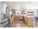Bright kitchen with stainless steel refrigerator, light wood cabinetry, and eat-in island with seating at 417 S Pontiac Way, Denver, CO 80210