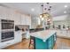 Open kitchen with white cabinets, a large island with seating, and stainless steel appliances at 2918 W 135Th Pl, Thornton, CO 80241