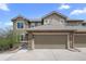 Charming townhouse featuring a stone-clad garage, neutral siding, and well-lit exterior at 22062 E Irish Dr, Aurora, CO 80016