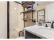 Bathroom with tiled shower, floating wood shelves, and an updated marble countertop at 2165 Summerlin Ln, Longmont, CO 80503