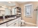 Bright bathroom featuring a white vanity with dark countertops, an updated shower, and floating shelves at 2165 Summerlin Ln, Longmont, CO 80503