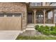 Charming home entrance with stone details, a covered porch, and a three-car garage at 2165 Summerlin Ln, Longmont, CO 80503