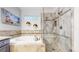 Bathroom featuring a soaking tub, frameless walk-in shower, and neutral tiles at 2266 S Kenton St, Aurora, CO 80014