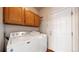 Functional laundry room with full-size washer and dryer, overhead cabinets, and a utility door at 2266 S Kenton St, Aurora, CO 80014