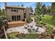 Backyard featuring a stone patio with outdoor seating, a wooden deck, and lush landscaping at 1456 Shavano Ct, Evergreen, CO 80439