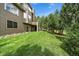 View of the house and backyard with large lawn and mature trees at 1456 Shavano Ct, Evergreen, CO 80439